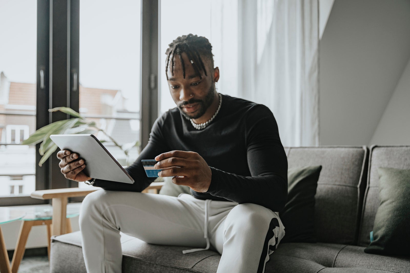 Man with tablet PC paying through credit card at home