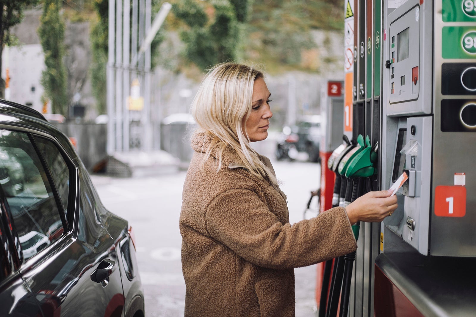 Mature woman doing payment via credit card at fuel station