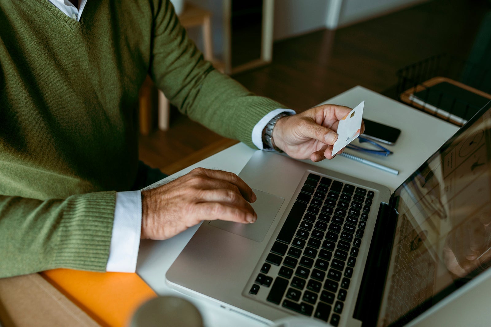 Midsection of mature man working on laptop while sitting at home
